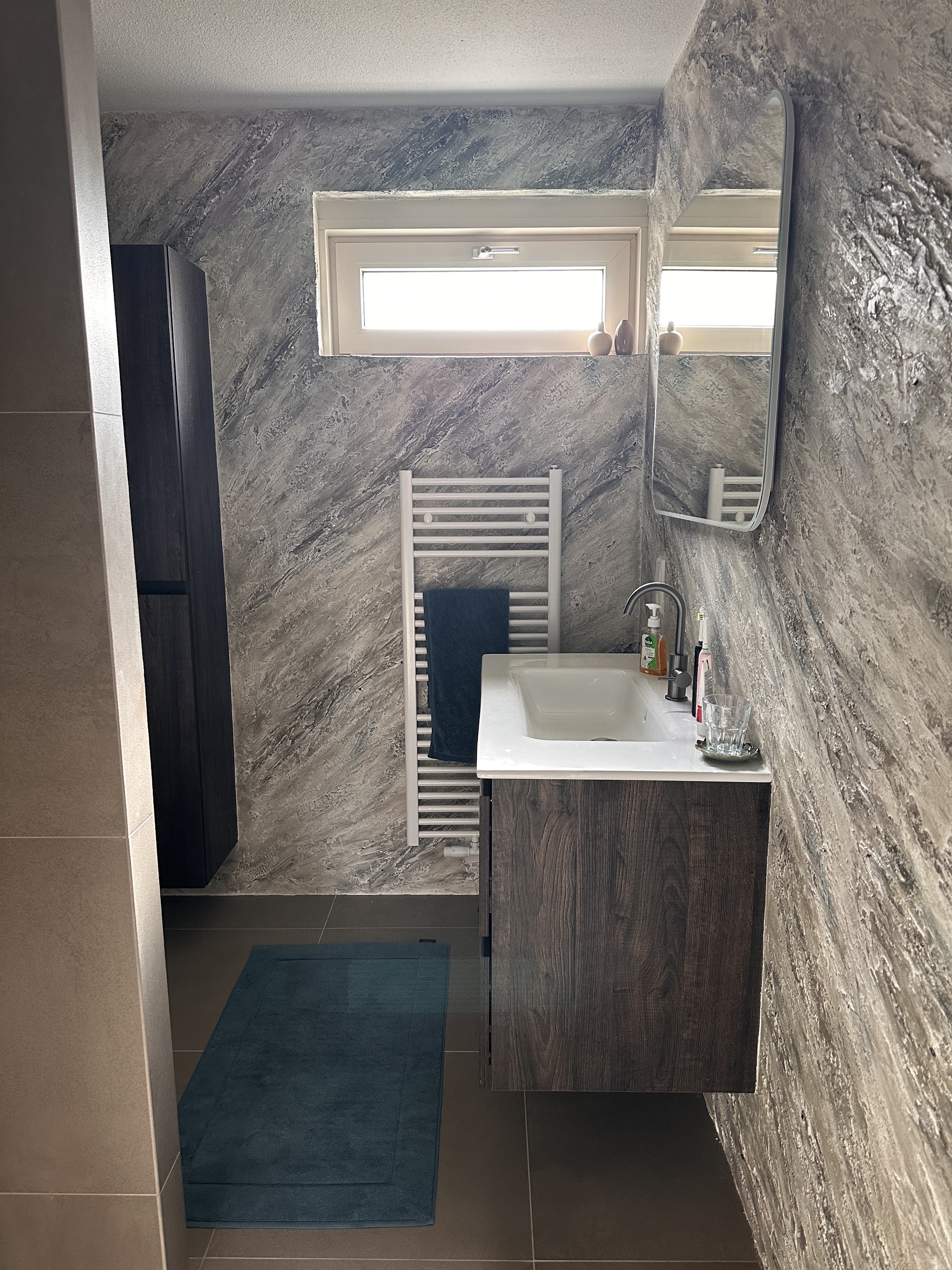 Badkamer met grijze decoratieve wandafwerking en wastafel