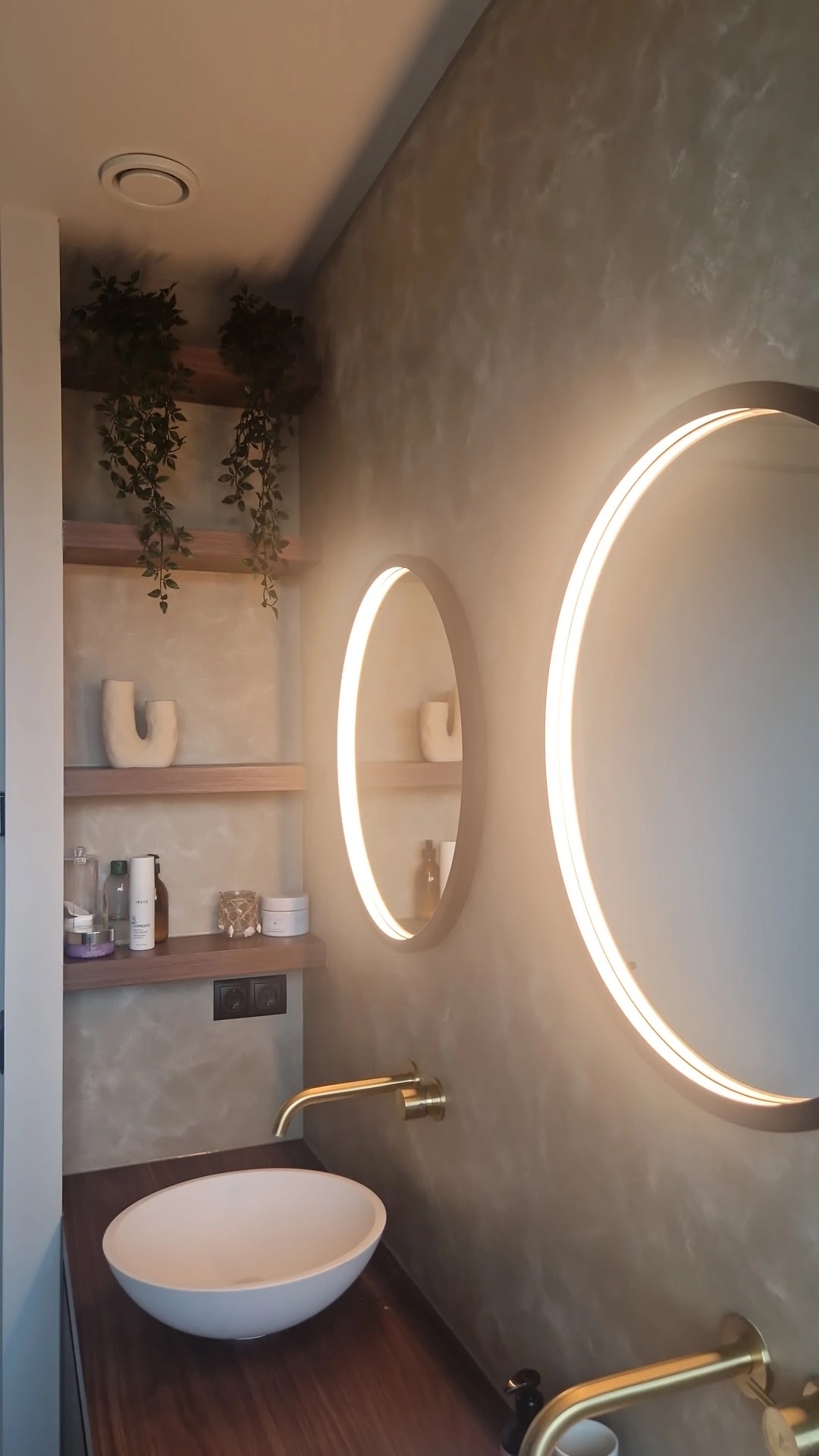 Badkamer met verlichte ronde spiegels voor een warme decoratieve wand